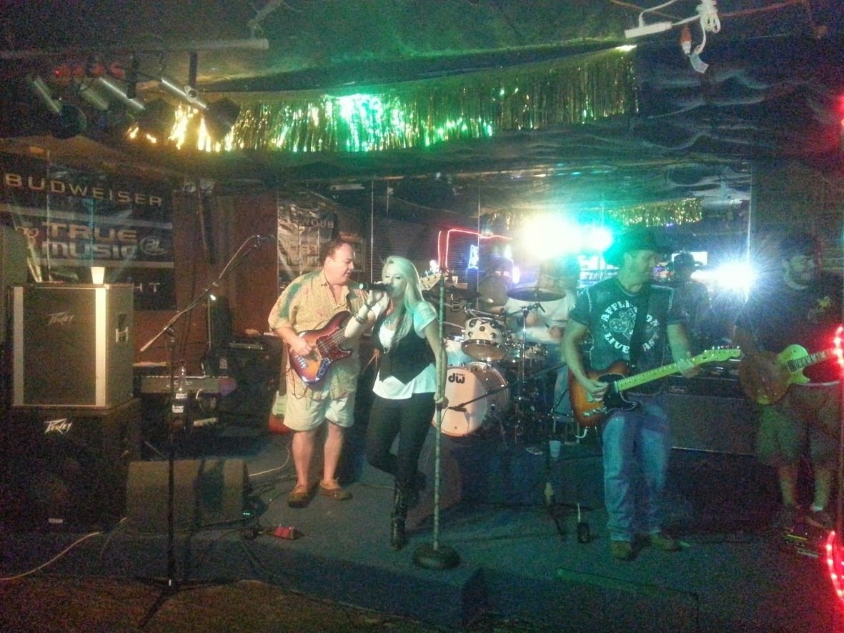 Full band performing live at a venue with Budweiser True Music signage