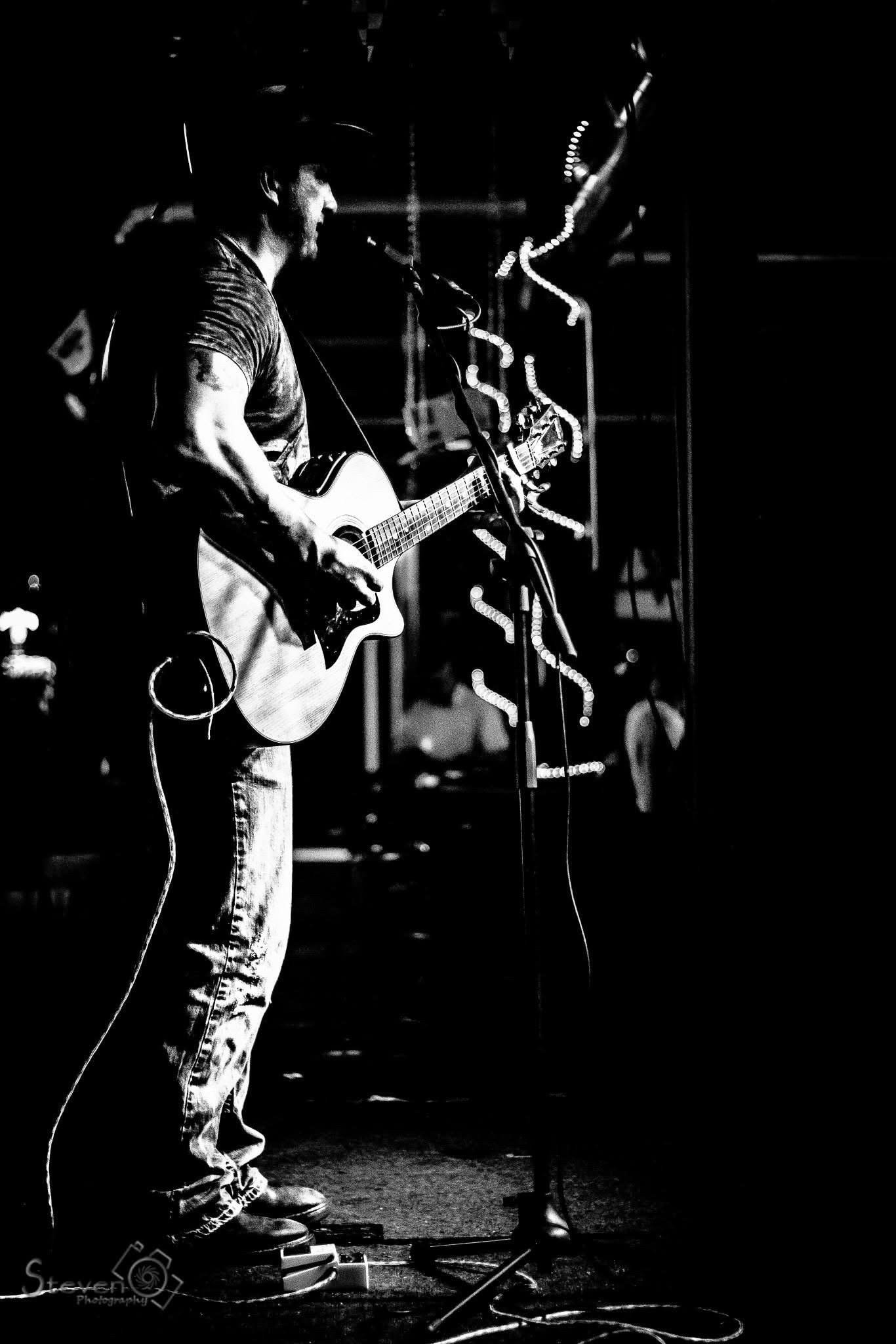 Full band performing in a bar with neon lights