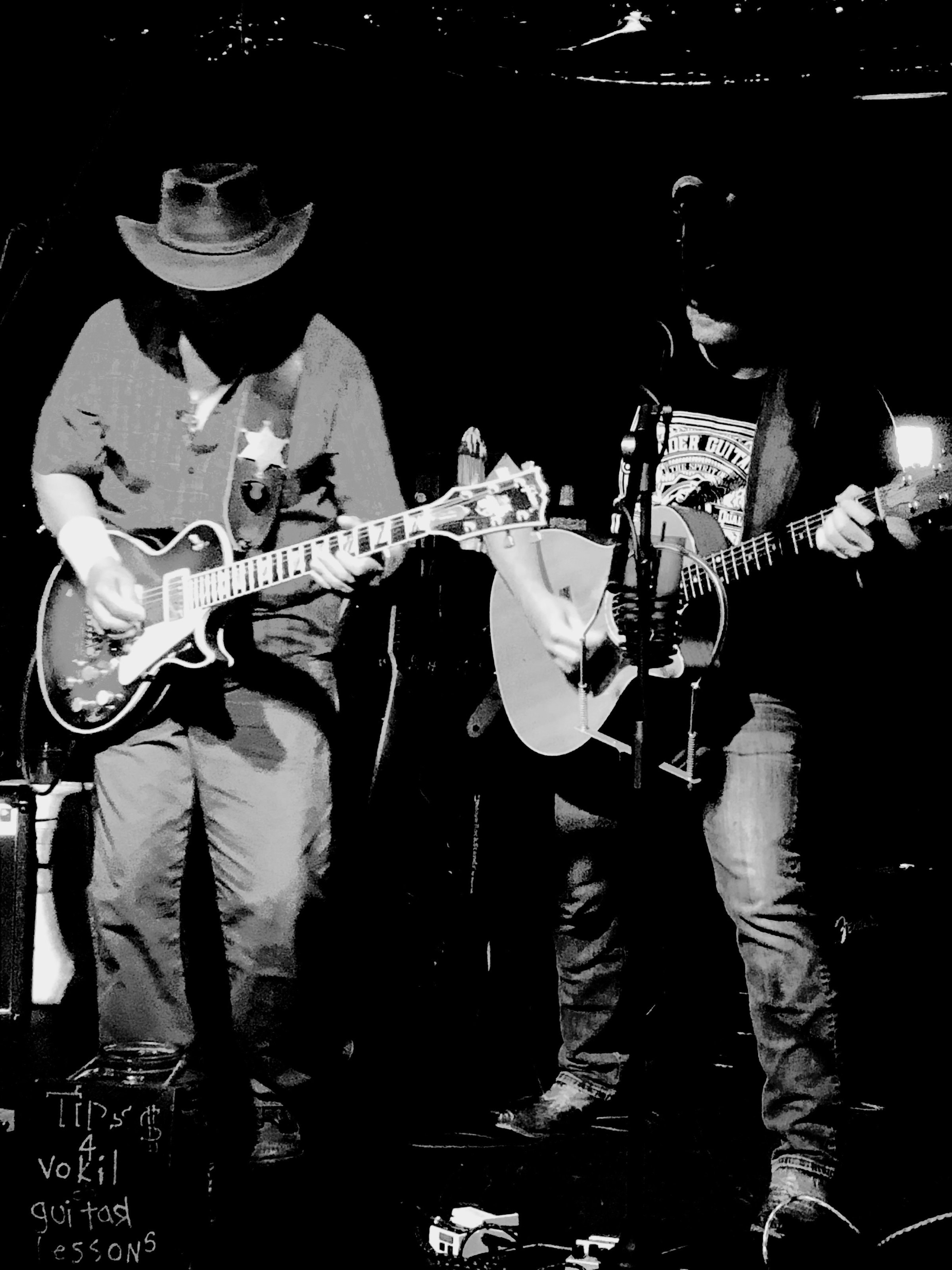 Guitarist silhouette from behind wearing a cowboy hat on stage