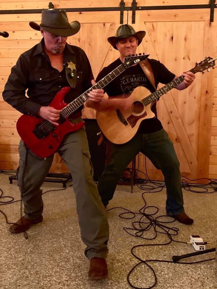 Marc Kenney and Jimmy Waters performing together in a wooden barn setting
