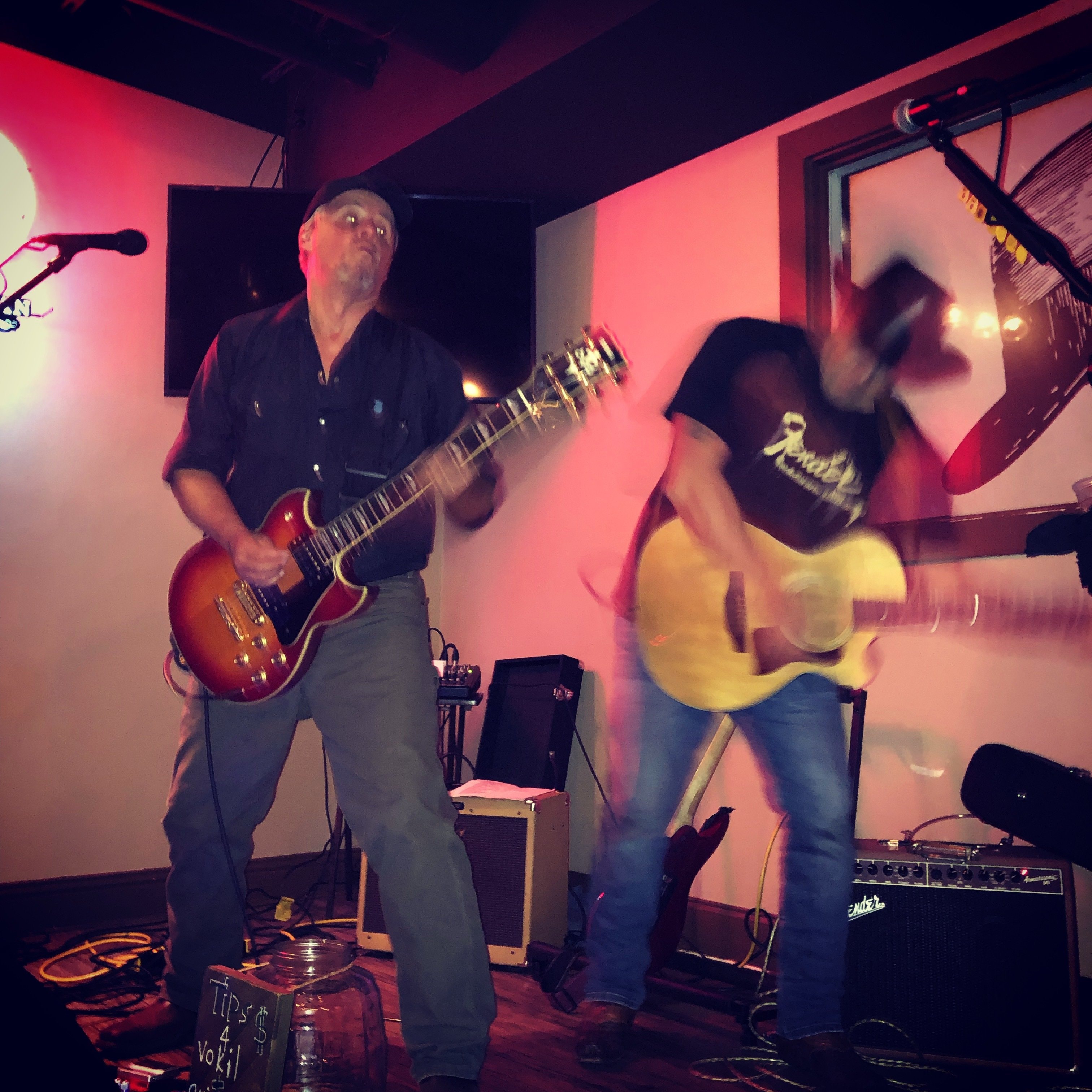Marc Kenney and Jimmy Waters performing live with pink/red ambient lighting