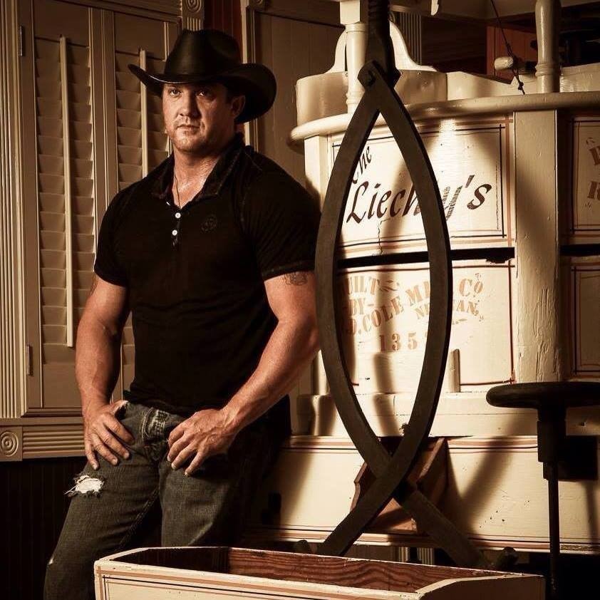 Marc Kenney in cowboy hat posing in rustic interior with vintage signage