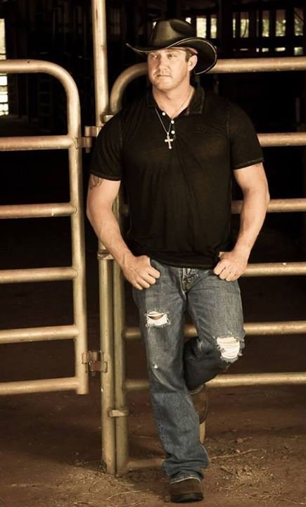 Marc Kenney performing live under red stage lighting, cowboy hat