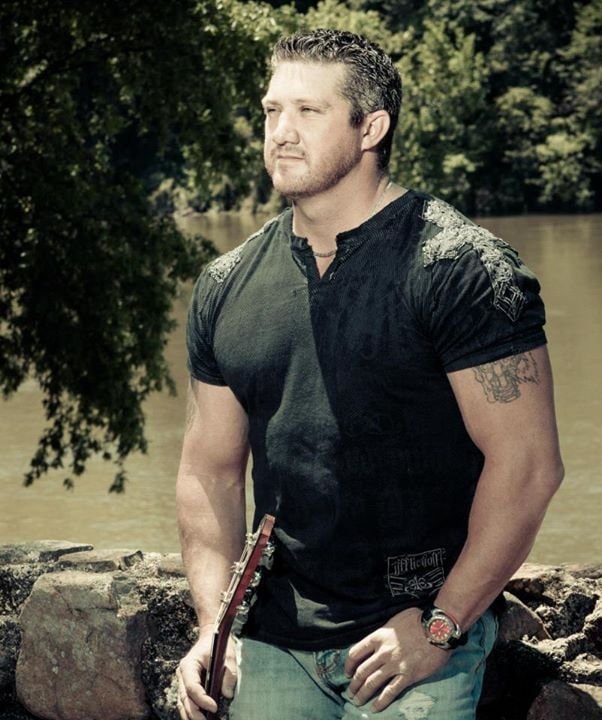 Marc Kenney performing live under red lighting, arm raised, Affliction vest