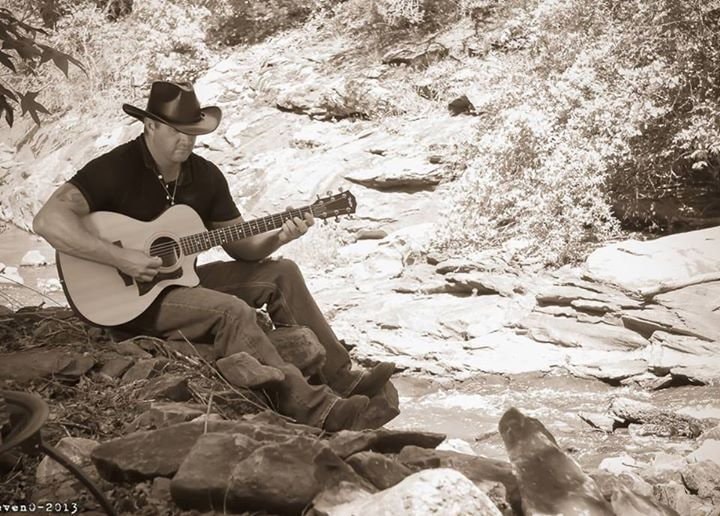 Marc Kenney performing live at microphone, sepia close-up with cowboy hat